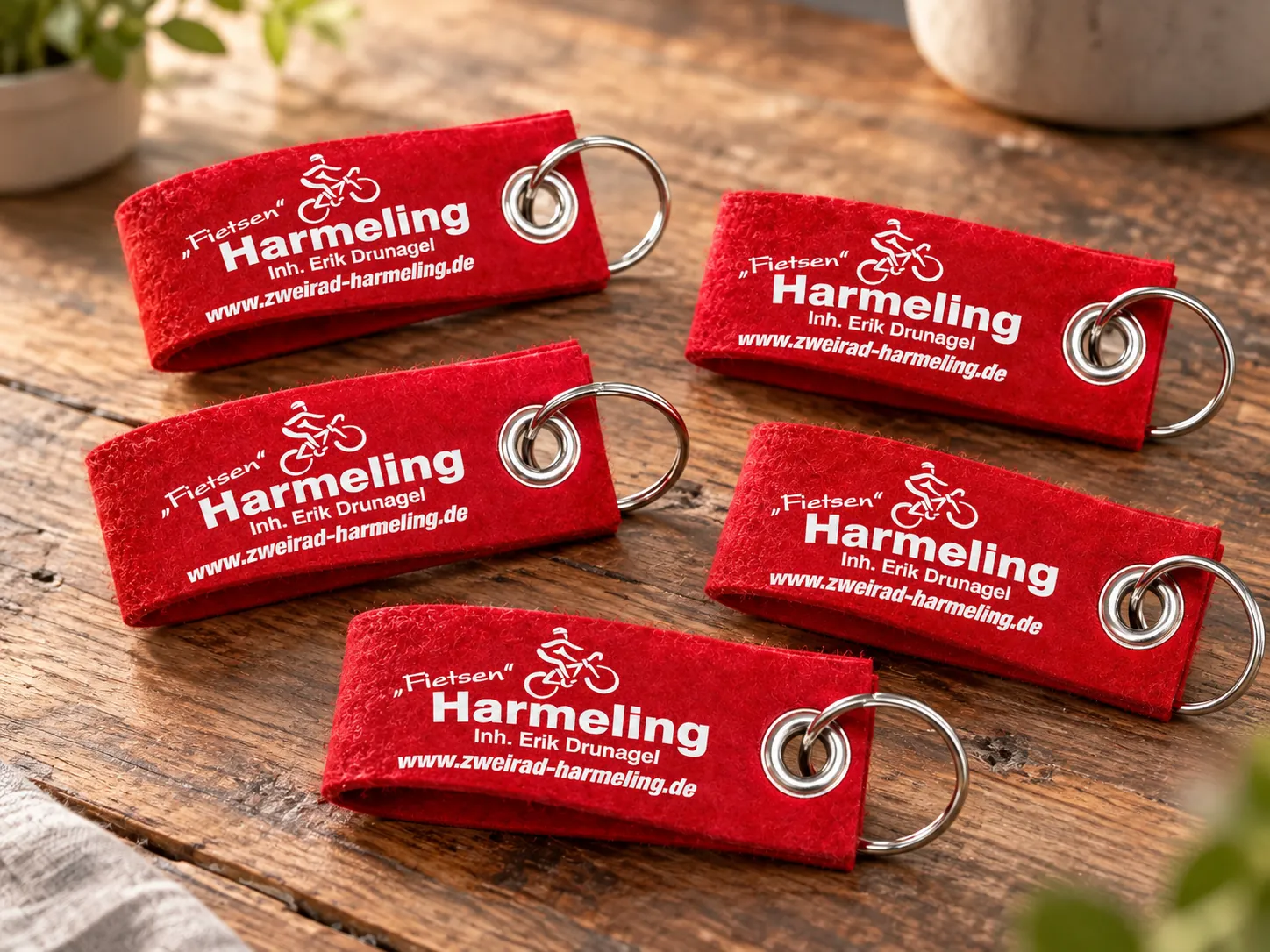 Rote Filz-Schlüsselanhänger mit weißem Logo von Zweirad Harmeling